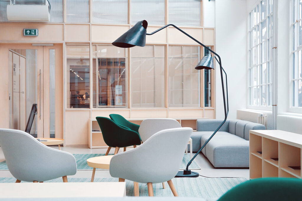 Scandinavian-style office space with light wood furniture, green chairs, and modern black pendant lighting