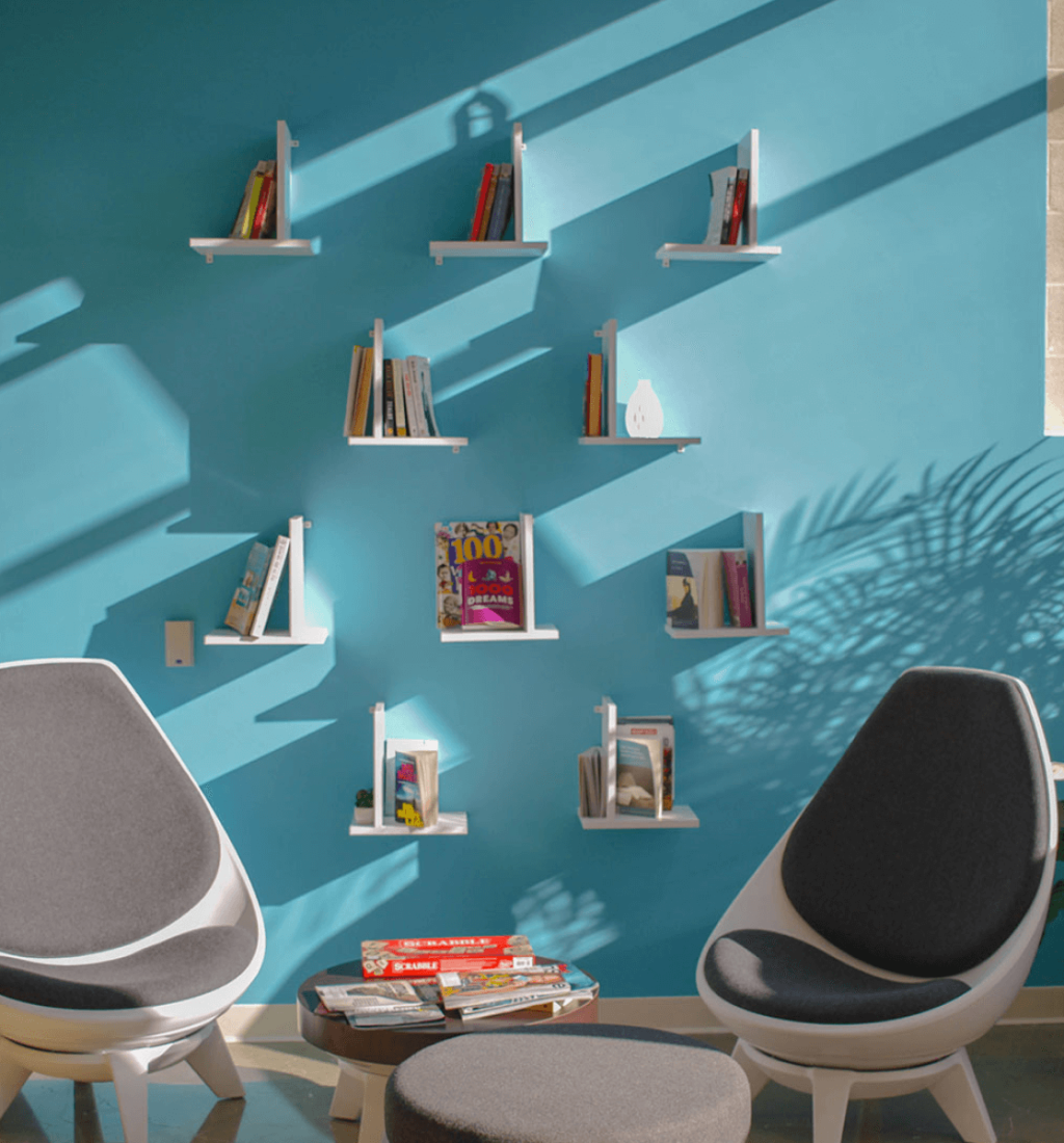 Modern blue accent wall with floating shelves and cozy seating – contemporary interior design